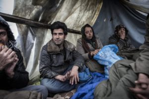  Afghan refugees sit under a plastic shelter in Subotica eating sandwiches donated by a local man. 